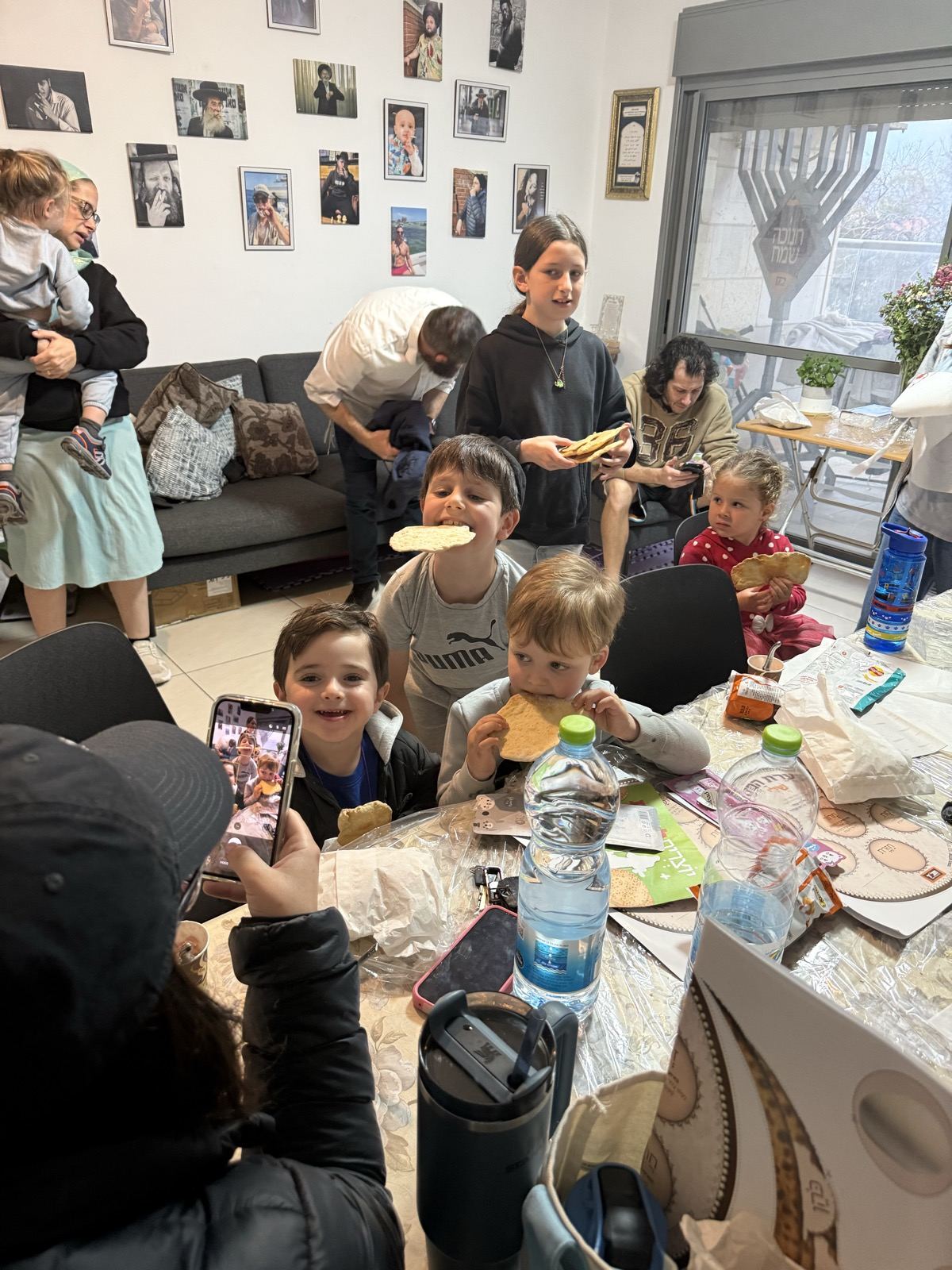 Children and parents around a table at a matzah baking activity at home