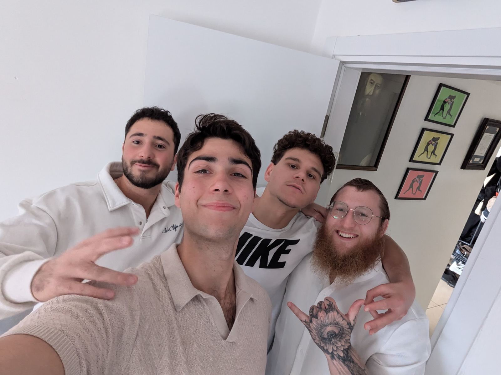 Four smiling young men posing for a selfie as guests at a Hadera home