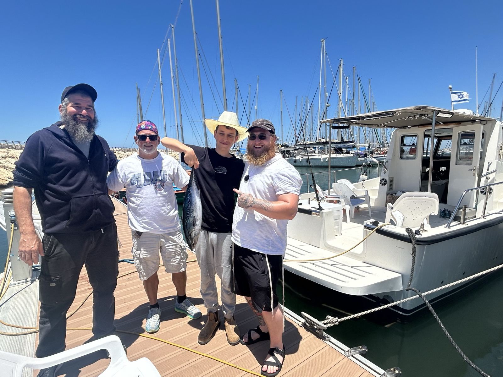 Four men smiling on the marina dock beside the boat before a fishing trip