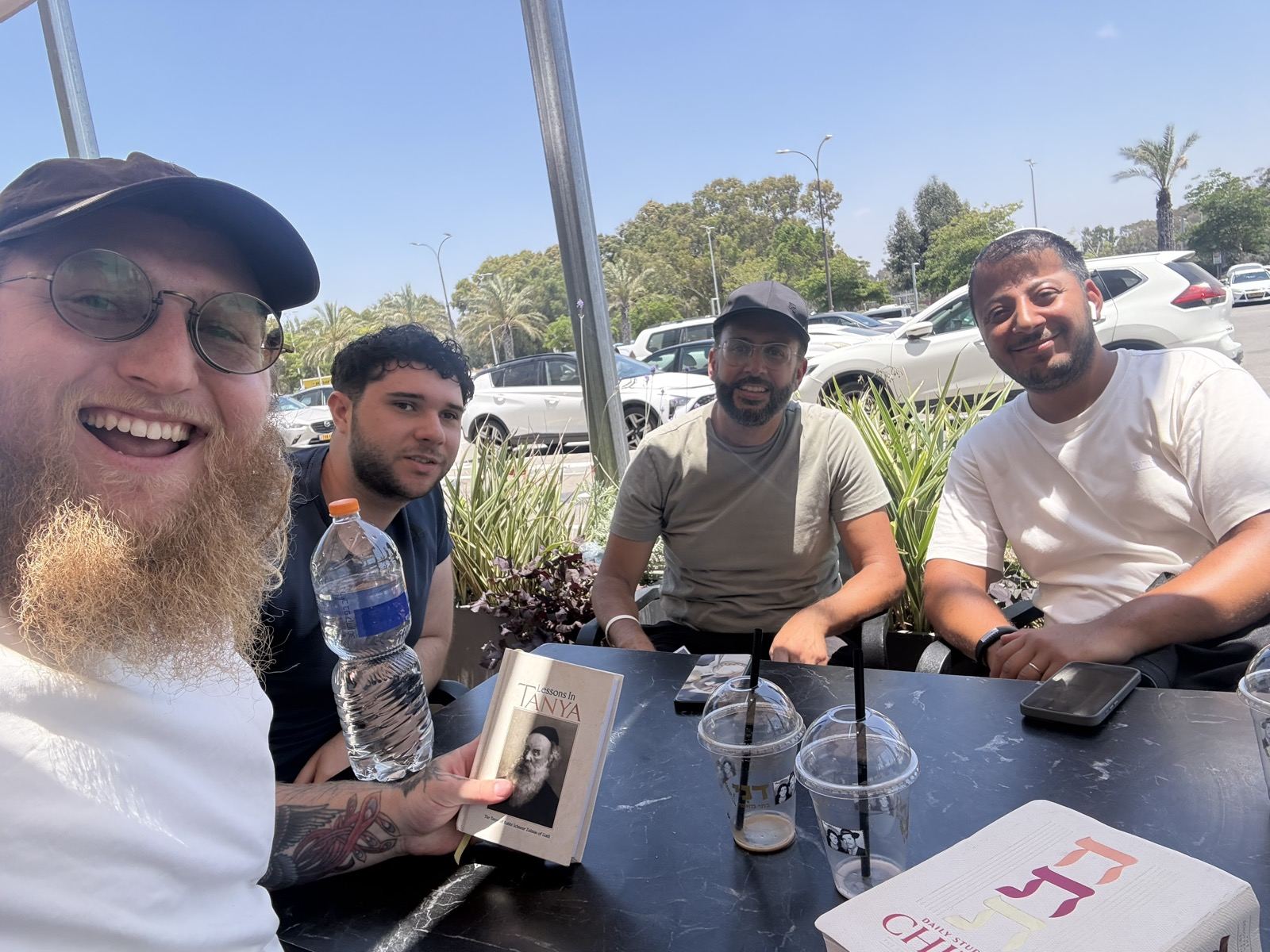 Four men smiling at a table at an outdoor cafe
