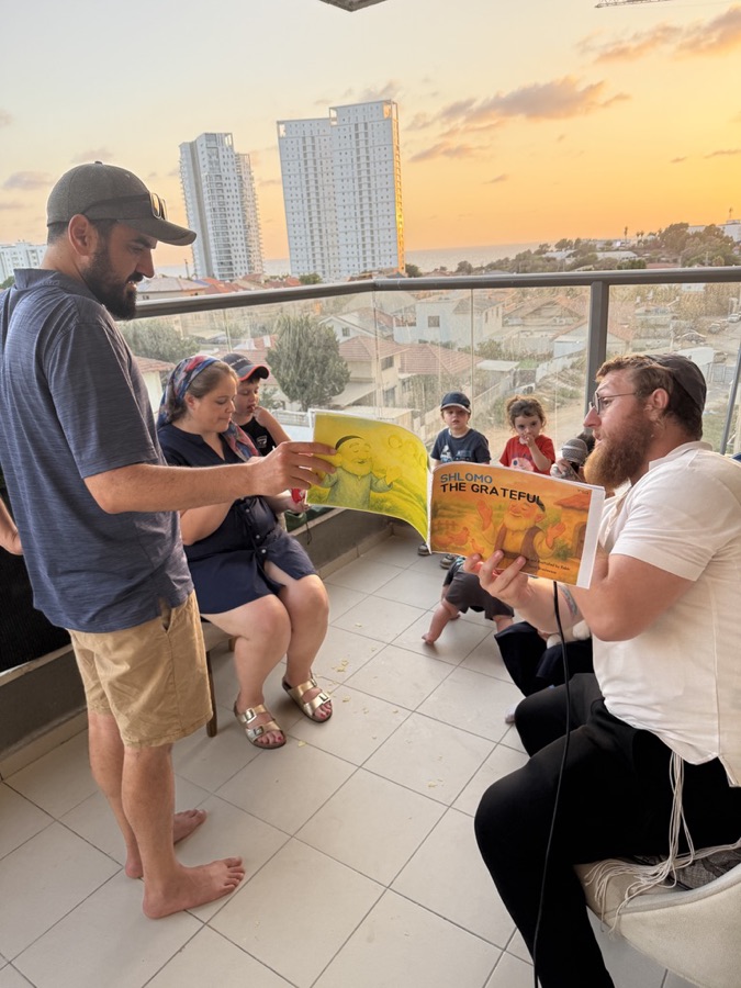 A children's story read aloud to families on a Hadera balcony at sunset