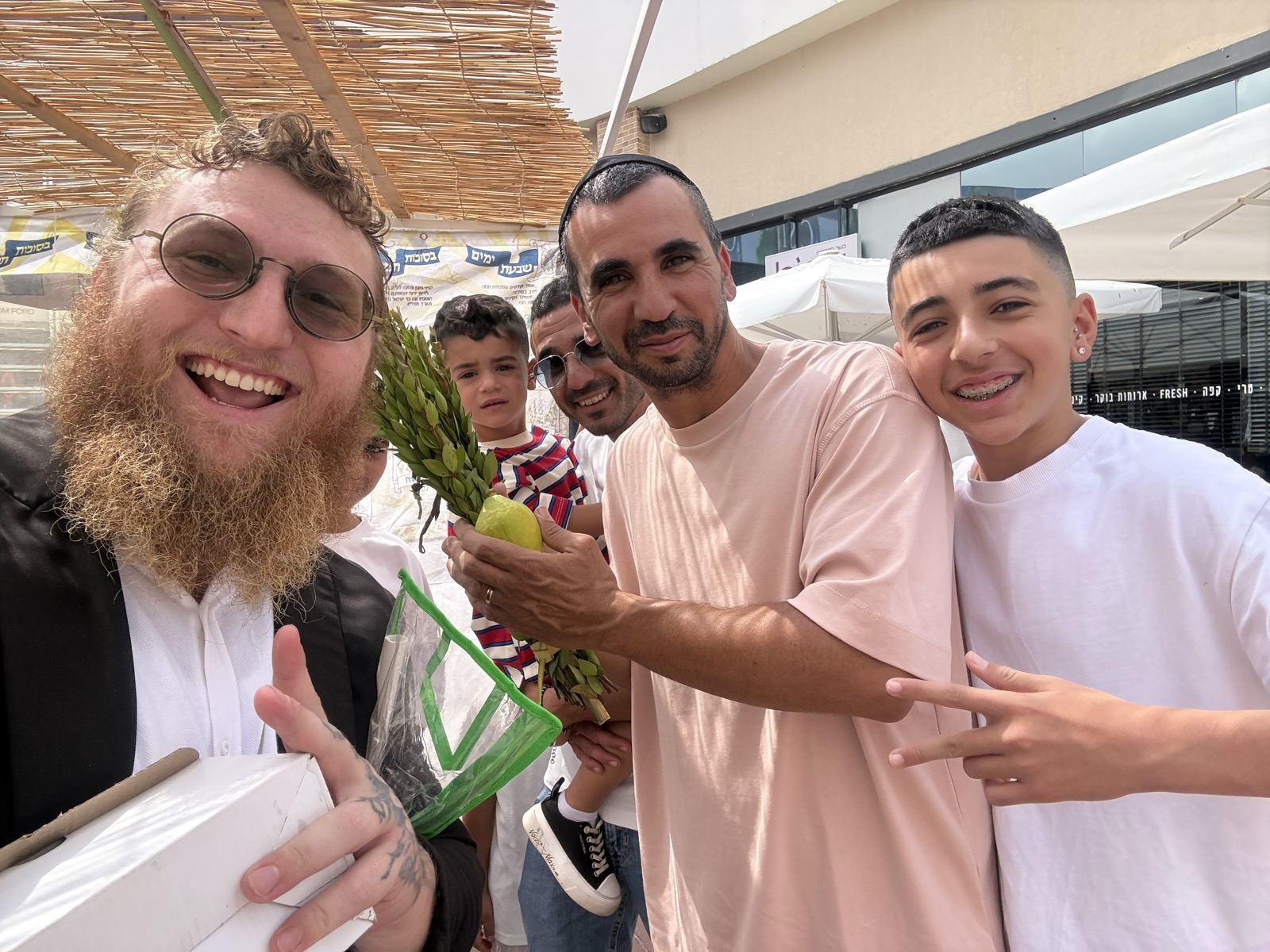 Friends on a Hadera street smiling and holding a lulav and etrog