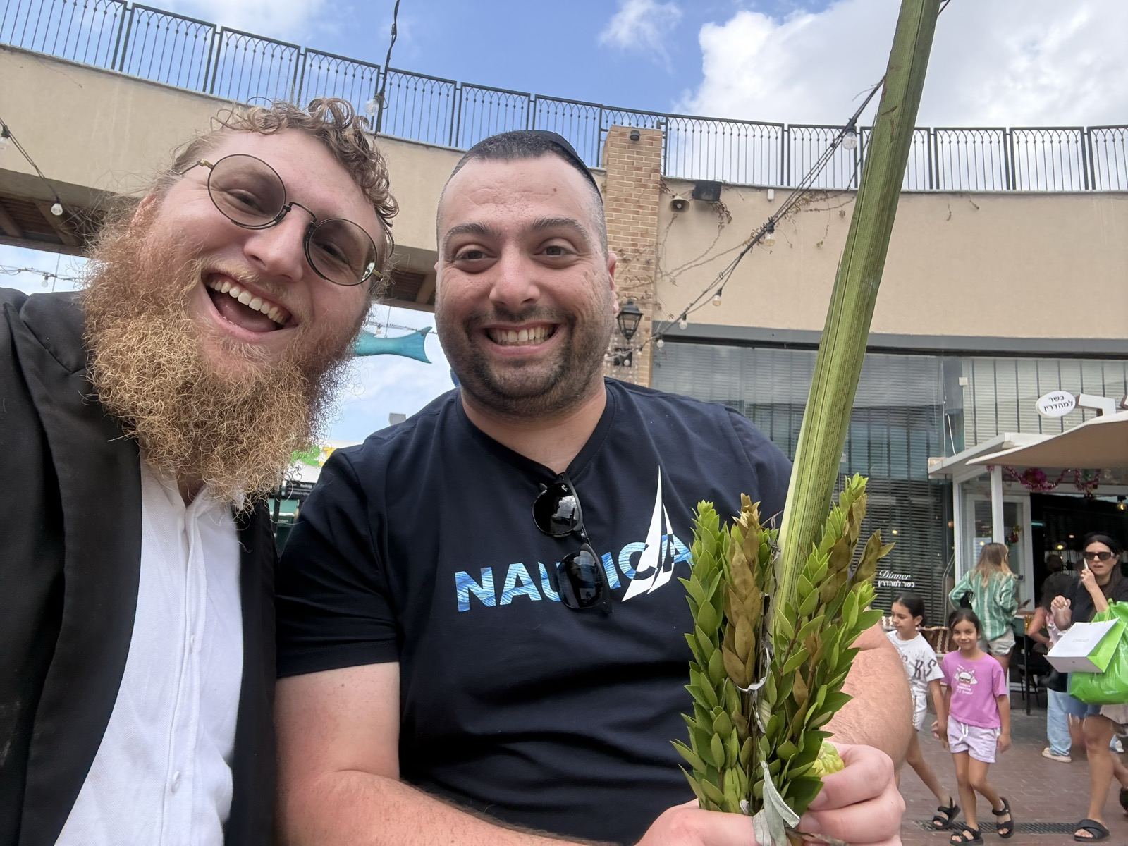 A man holding a lulav and smiling in a Hadera shopping center