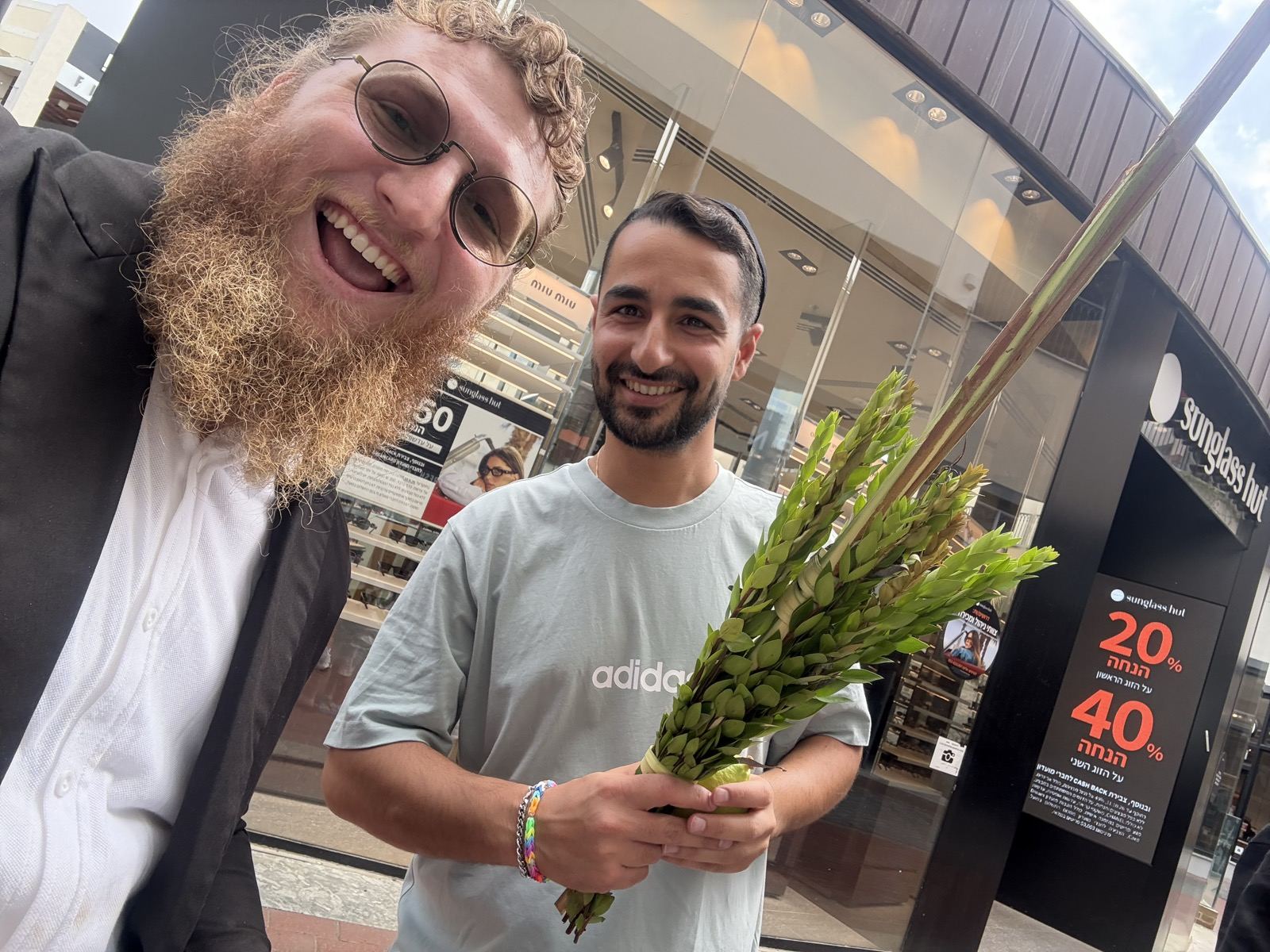 A man in a grey shirt holding a lulav and etrog