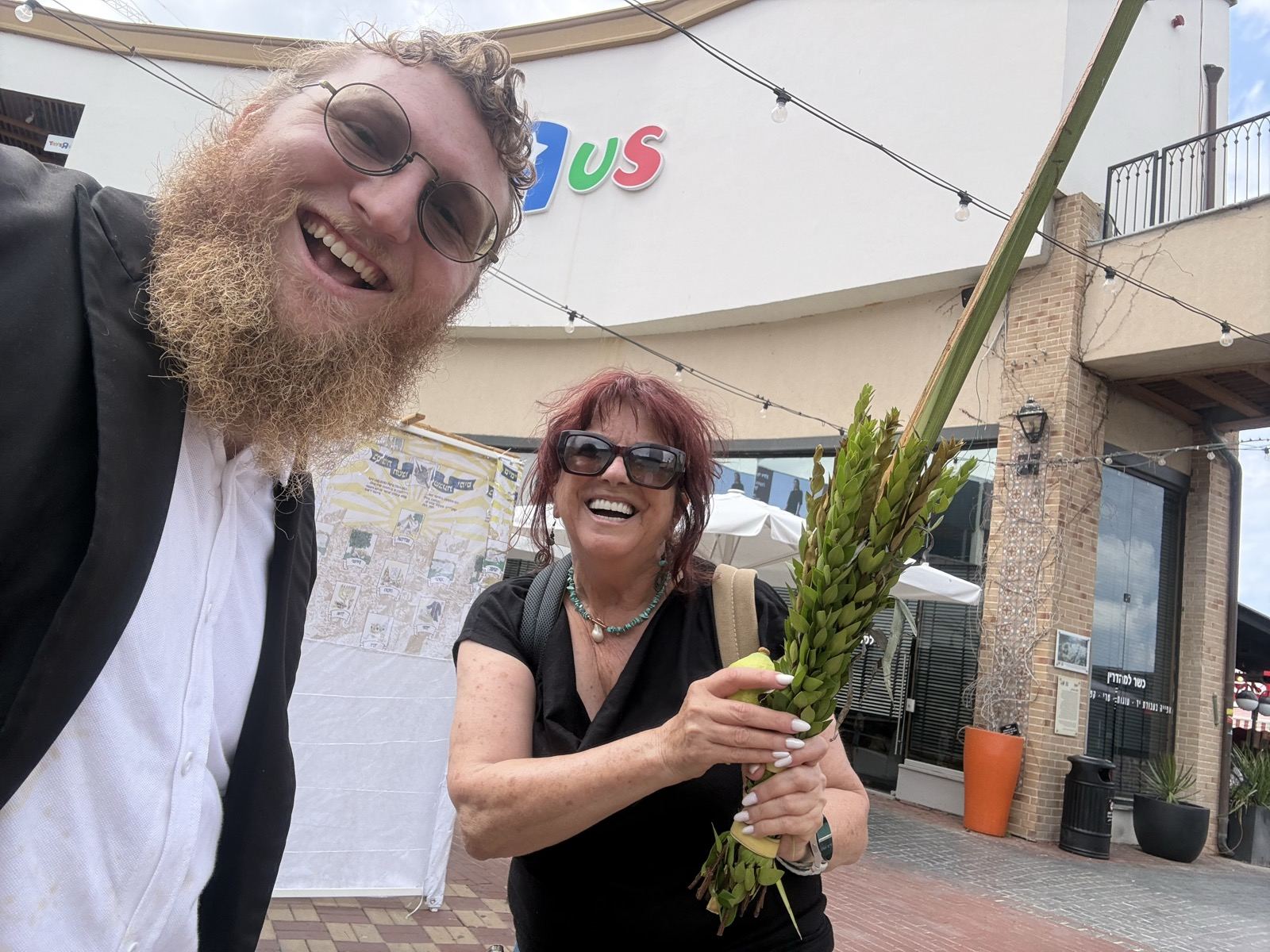 A woman smiling and holding a lulav outside a store
