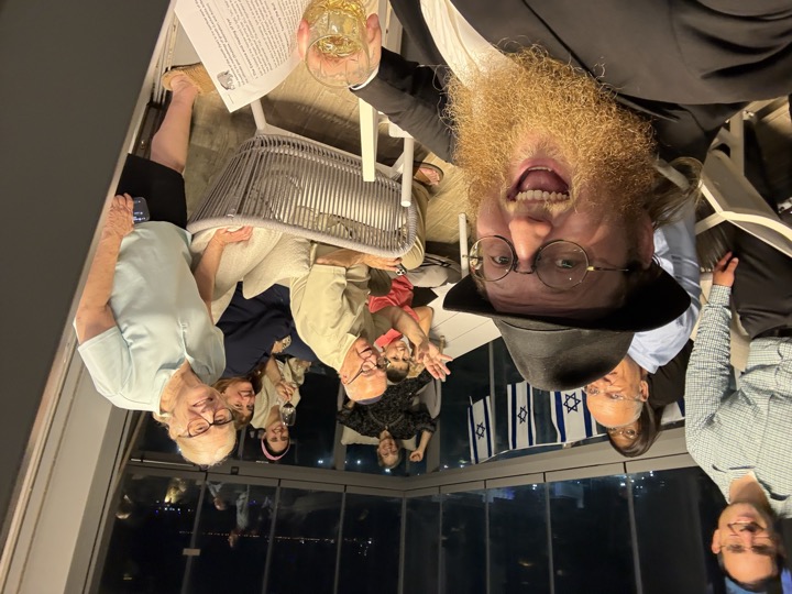 Smiling community members gathered together on a balcony in Hadera at night