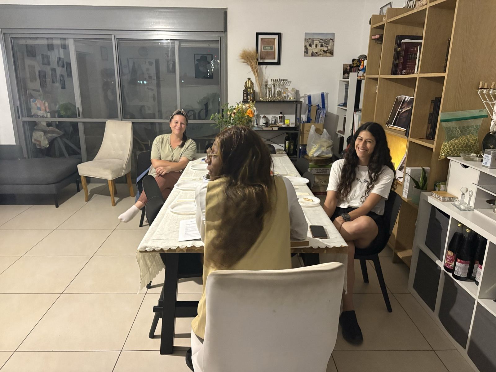 Women smiling and talking around a long table at a community evening